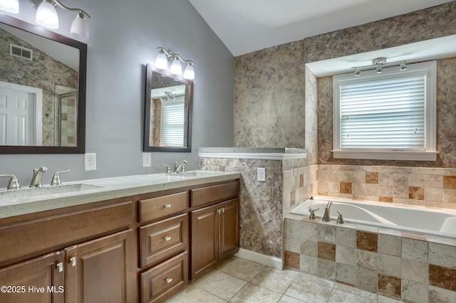 bathroom featuring visible vents, plenty of natural light, a sink, and a garden tub