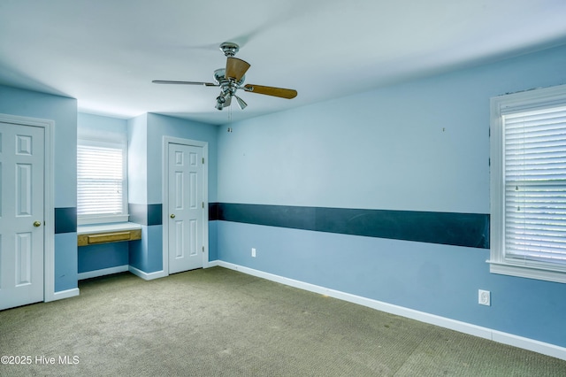 unfurnished bedroom with carpet flooring, baseboards, two closets, and ceiling fan