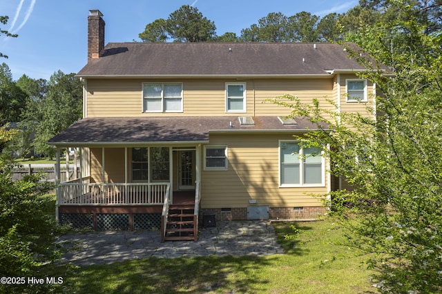 back of property with a lawn, a patio, a chimney, and crawl space