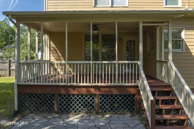 view of exterior entry featuring covered porch and fence