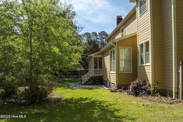 view of side of property featuring a lawn, fence, and a chimney