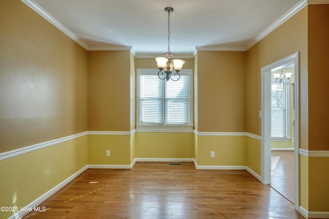 spare room featuring baseboards, ornamental molding, hardwood / wood-style flooring, and a notable chandelier