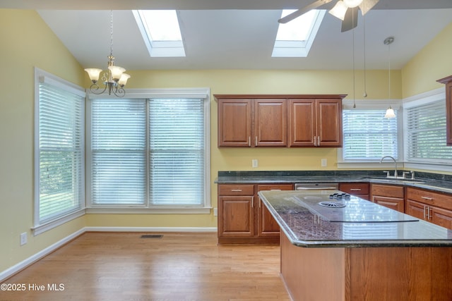 kitchen featuring a sink, light wood-style floors, lofted ceiling with skylight, and visible vents