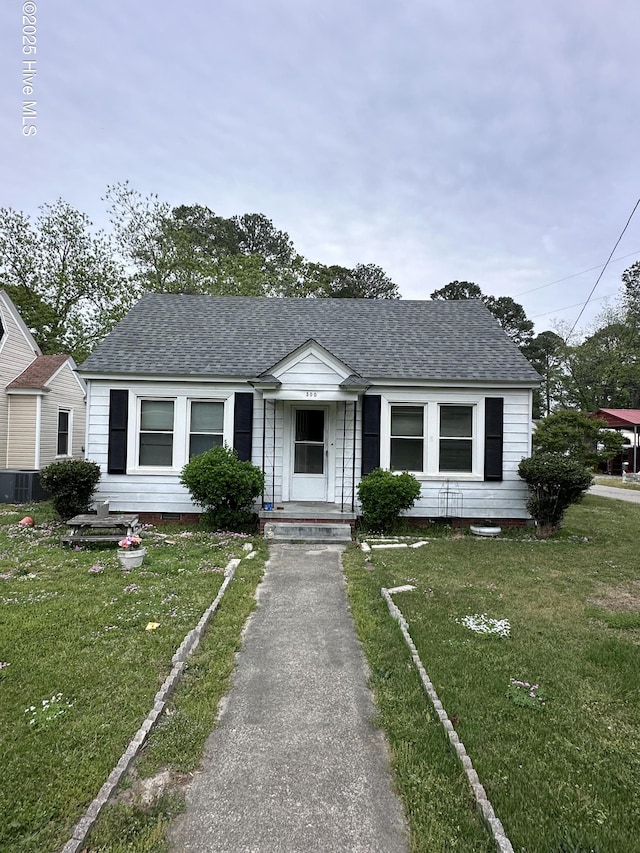 300 W Bryant St, Enfield, NC 27823 - bungalow-style house with central AC unit, roof with shingles, and a front lawn