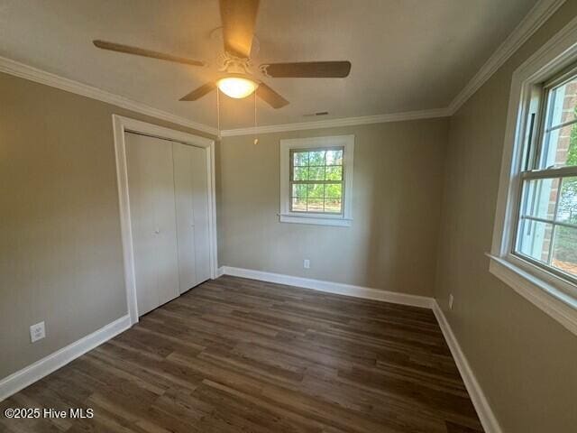 unfurnished bedroom featuring dark wood finished floors, baseboards, a closet, ceiling fan, and ornamental molding