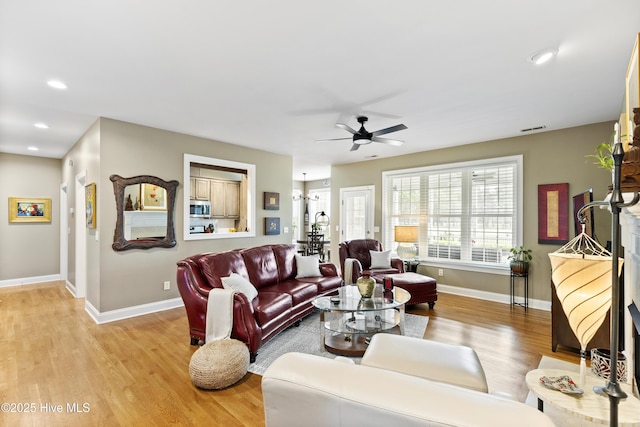 living room featuring light wood finished floors, a ceiling fan, baseboards, recessed lighting, and visible vents