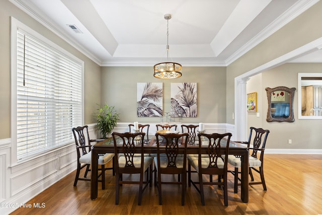 dining space with visible vents, wainscoting, wood finished floors, a tray ceiling, and a chandelier