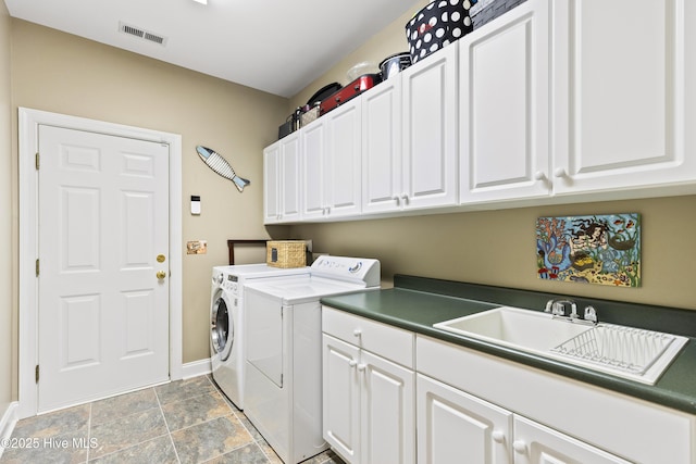 laundry area with cabinet space, a sink, baseboards, visible vents, and washing machine and dryer