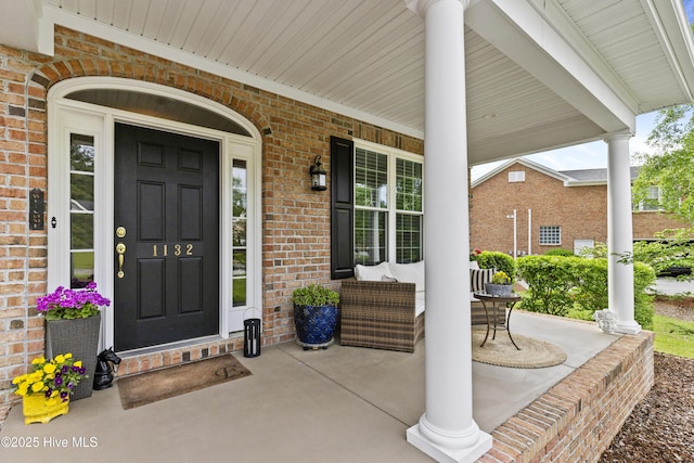 entrance to property with covered porch and brick siding