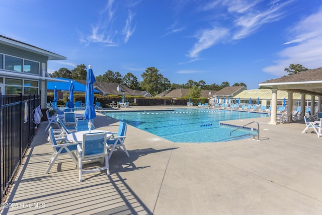 community pool with a patio area and fence