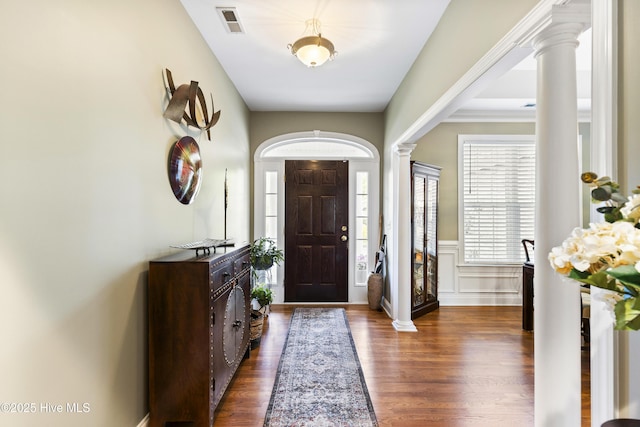 entrance foyer with decorative columns, visible vents, dark wood finished floors, a wainscoted wall, and a decorative wall