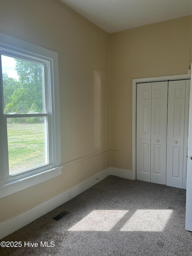 unfurnished bedroom featuring visible vents, carpet floors, a closet, and multiple windows