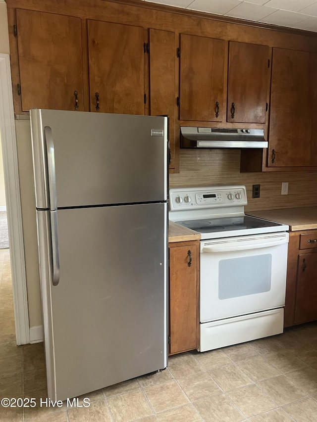 kitchen featuring white range with electric cooktop, brown cabinets, light countertops, under cabinet range hood, and freestanding refrigerator