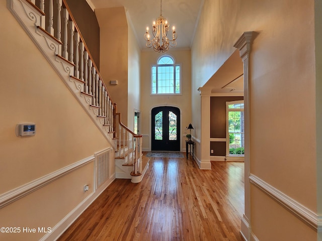 entrance foyer featuring stairs, wood finished floors, baseboards, a high ceiling, and a notable chandelier