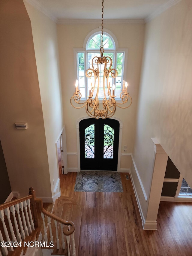 foyer with crown molding, baseboards, a notable chandelier, and wood finished floors