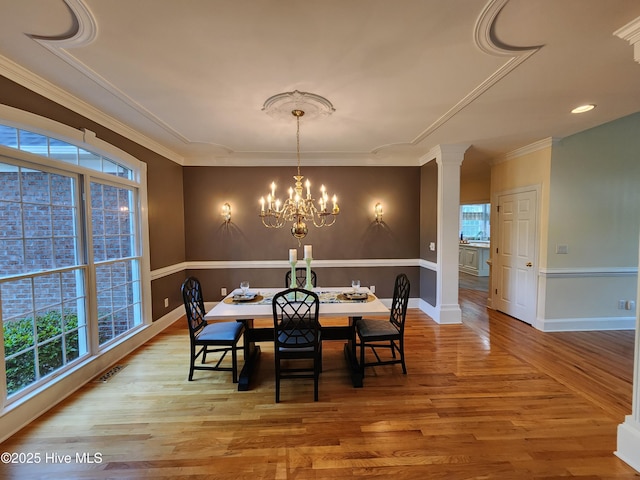 dining room featuring plenty of natural light, wood finished floors, visible vents, and an inviting chandelier