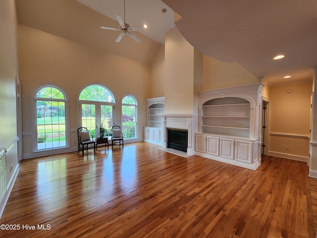 unfurnished living room featuring high vaulted ceiling, a fireplace, a ceiling fan, and wood finished floors