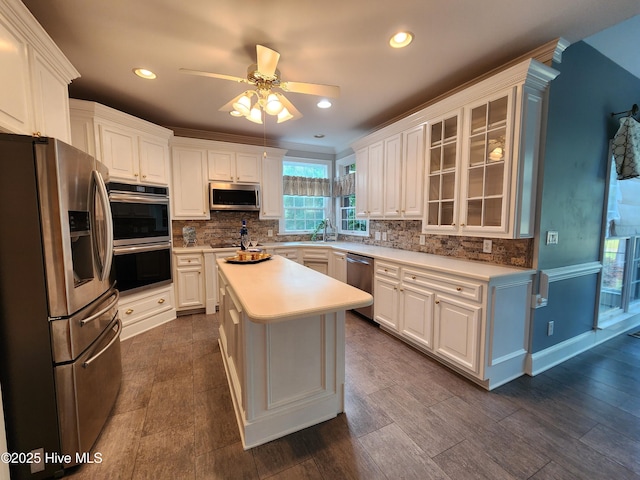 kitchen featuring light countertops, stainless steel appliances, a ceiling fan, and decorative backsplash