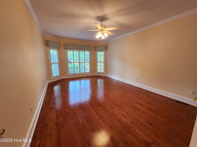 unfurnished room with ornamental molding, a ceiling fan, baseboards, visible vents, and dark wood-style floors