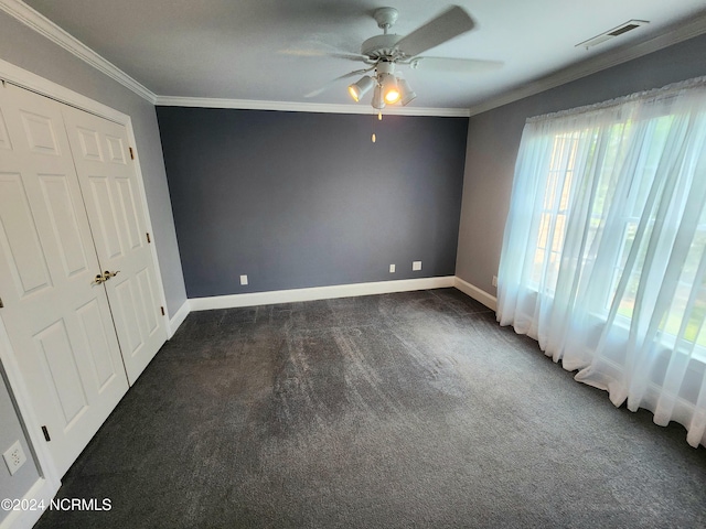 unfurnished bedroom with a ceiling fan, visible vents, baseboards, ornamental molding, and dark carpet