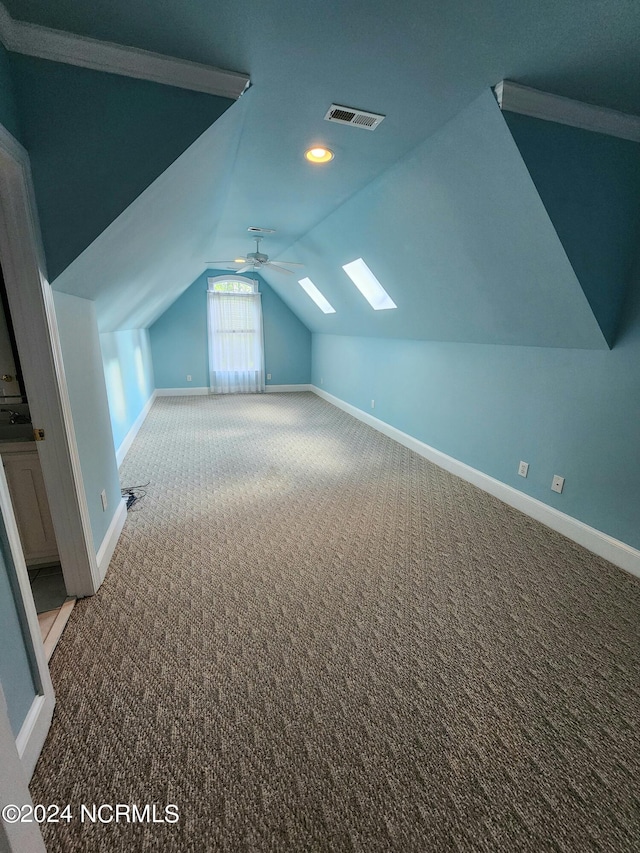 bonus room featuring carpet floors, baseboards, vaulted ceiling with skylight, and visible vents