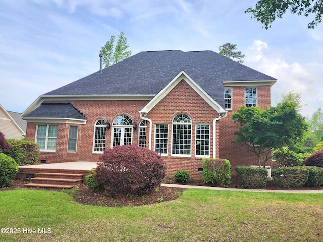view of front of property with brick siding, crawl space, roof with shingles, and a front yard