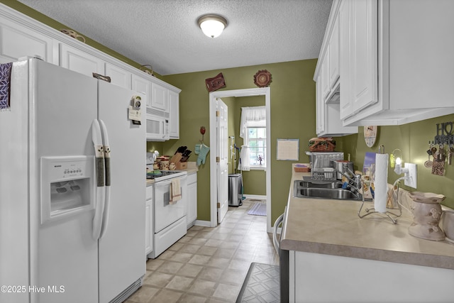 kitchen with white appliances, a sink, white cabinetry, a textured ceiling, and light floors
