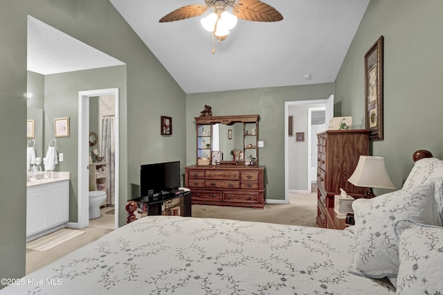 bedroom with lofted ceiling, light colored carpet, a ceiling fan, ensuite bathroom, and baseboards