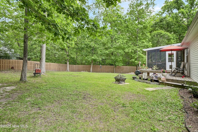 view of yard with a sunroom, a fire pit, and a deck