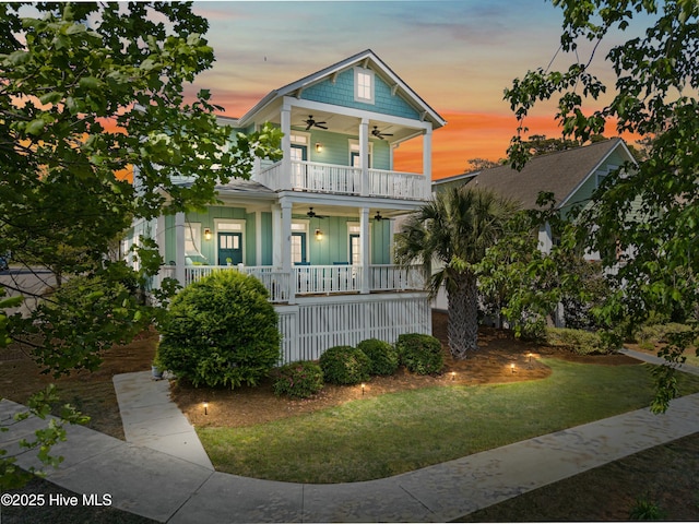 6439 Stopper Ln SW, Ocean Isle Beach, NC 28469 - view of front facade featuring a ceiling fan, a balcony, a front yard, and covered porch