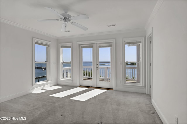 carpeted spare room with crown molding, visible vents, a water view, and baseboards