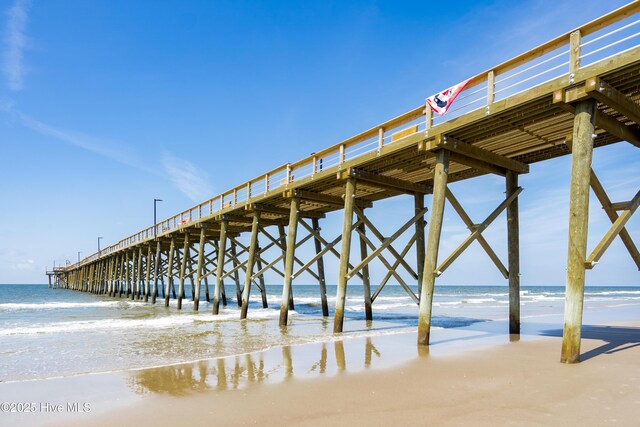 dock area with a pier, a water view, and a view of the beach