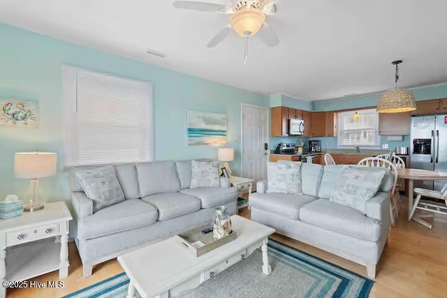 living room with light wood-type flooring and a ceiling fan