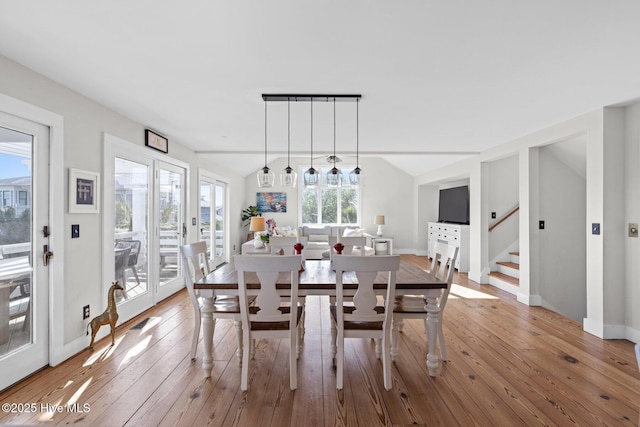 dining area featuring stairway, wood-type flooring, vaulted ceiling, and visible vents