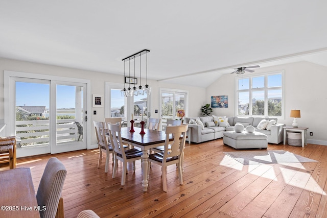 dining area with a ceiling fan, vaulted ceiling, and light wood-type flooring