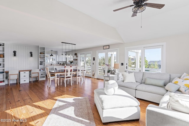 living area featuring wood-type flooring, ceiling fan, and lofted ceiling