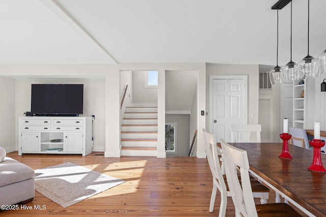 living area with baseboards, light wood-style flooring, and stairway