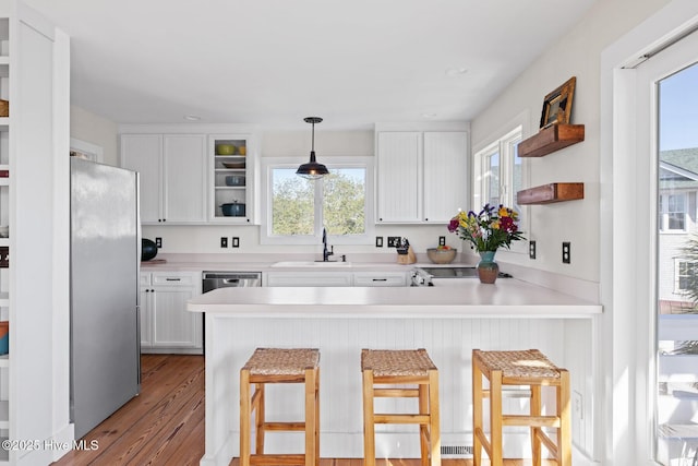 kitchen featuring open shelves, a sink, white cabinets, a peninsula, and stainless steel appliances