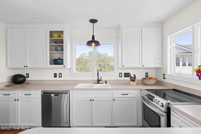 kitchen with white cabinets, stainless steel appliances, pendant lighting, and a sink