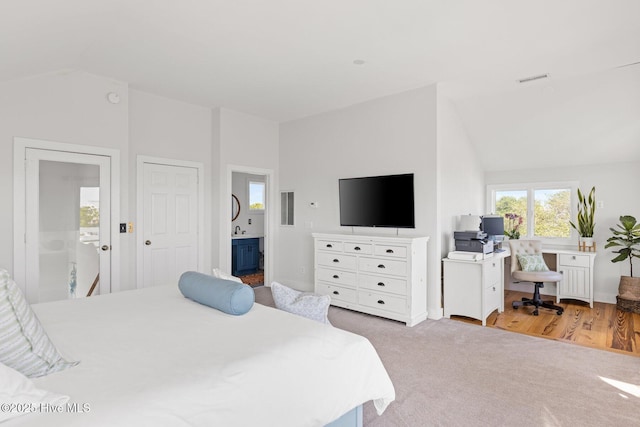 bedroom featuring visible vents, carpet flooring, connected bathroom, and lofted ceiling