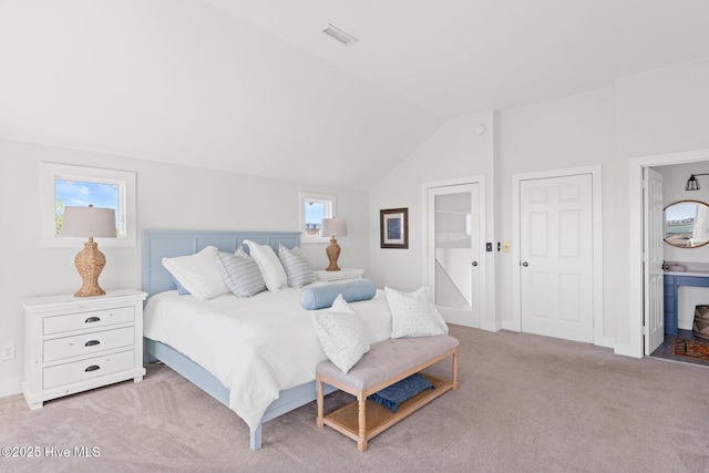 carpeted bedroom with vaulted ceiling, ensuite bath, and visible vents