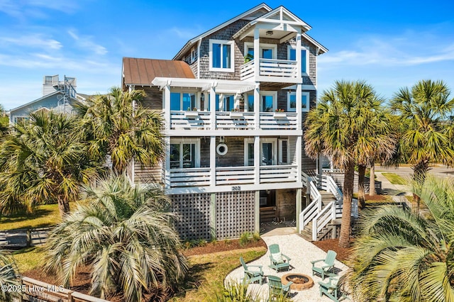 view of front of house with a standing seam roof, a balcony, a pergola, a fire pit, and stairs