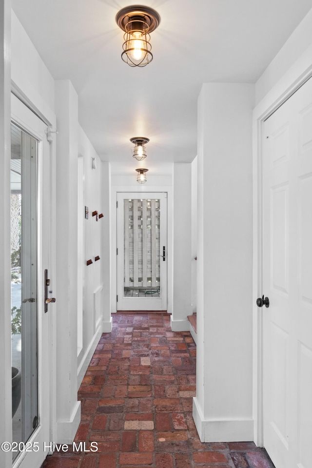 hall featuring baseboards and brick floor