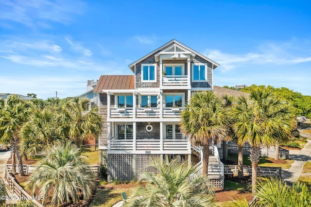 back of property featuring metal roof, stairs, a balcony, and a standing seam roof
