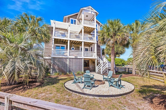 rear view of property featuring stairway, fence, a balcony, and an outdoor fire pit