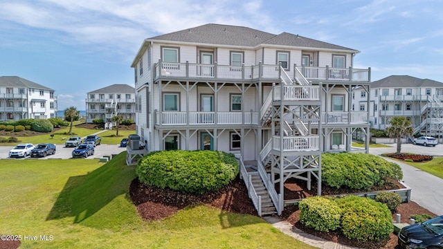 view of front of home featuring stairway, cooling unit, uncovered parking, and a front lawn