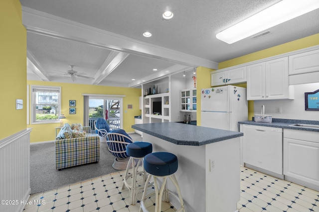 kitchen with light floors, dark countertops, and white appliances