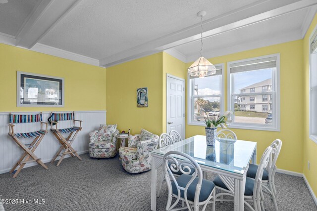 carpeted dining room with a textured ceiling, a chandelier, and beamed ceiling