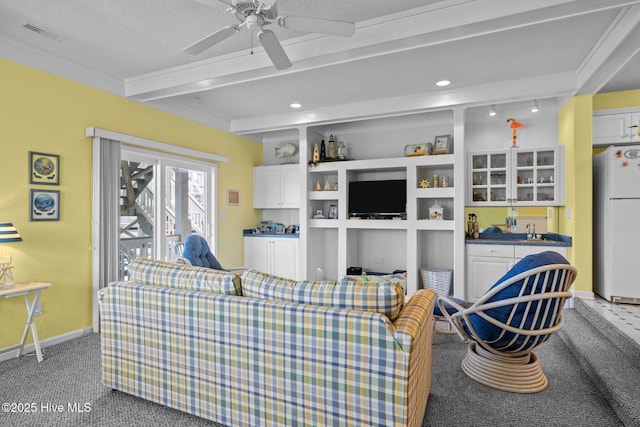 living area featuring carpet flooring, visible vents, ceiling fan, baseboards, and beam ceiling