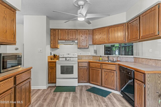 kitchen featuring stainless steel microwave, electric stove, brown cabinets, a sink, and dishwasher